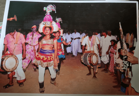 A few women dancing surrounded by male onlookers and musicians 
